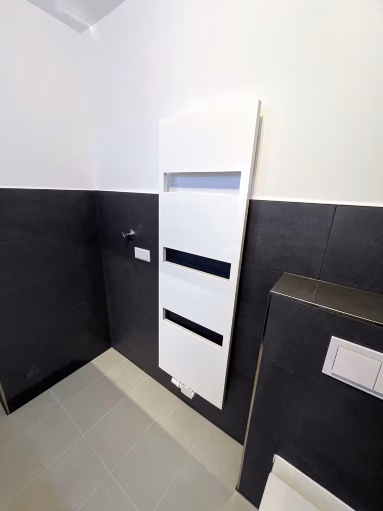Design-Handtuchheizkörper in Weiß vor Wandfliesen in Anthrazit