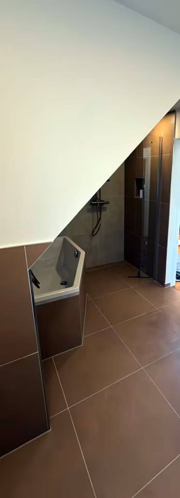 Walk-in-Dusche und Badewanne unter der Dachschräge mit Fliesen in Terrakotta